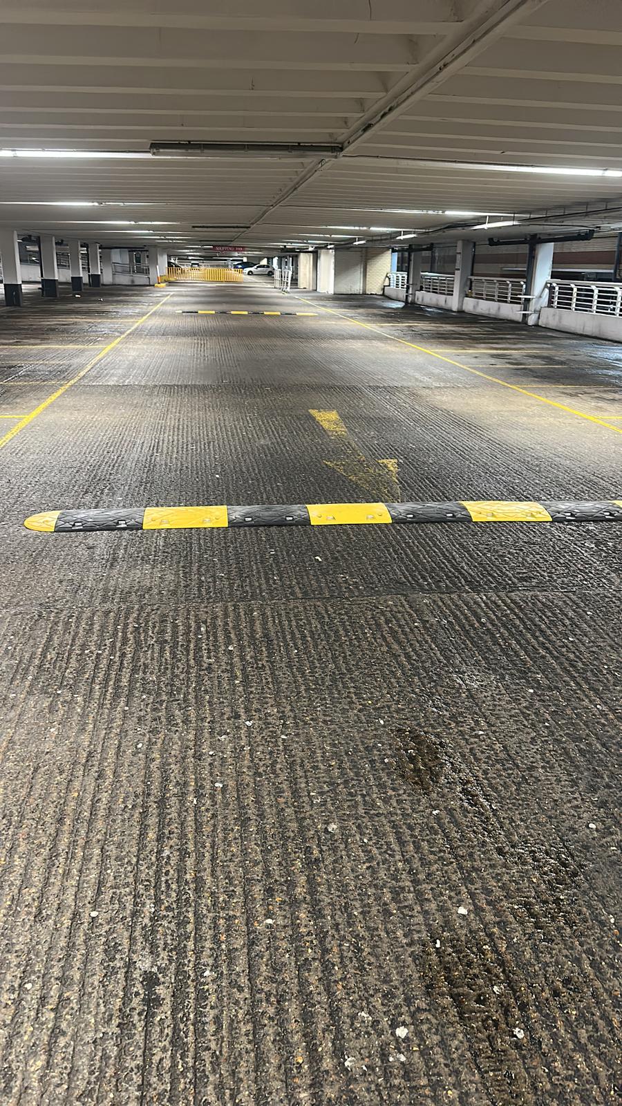 Traffic calming speed bump spanning a car park drive lane with yellow bay markings