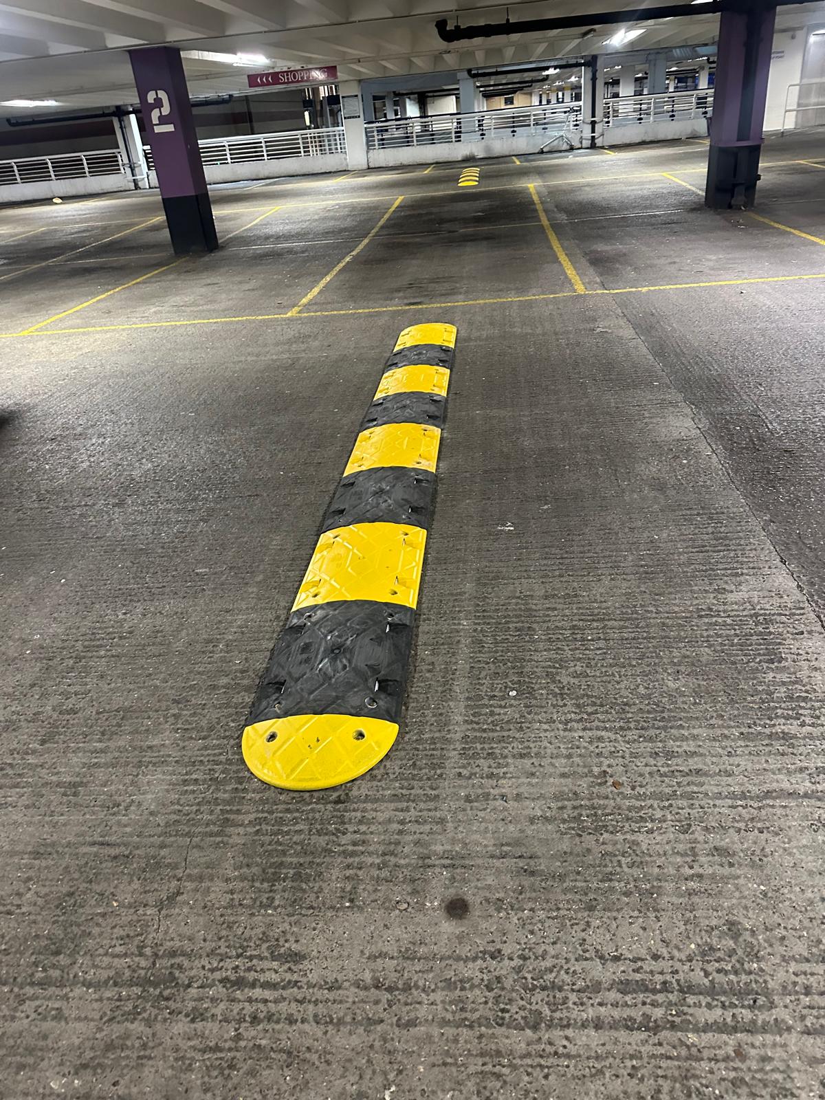 Modular rubber speed ramp fitted across an indoor car park aisle