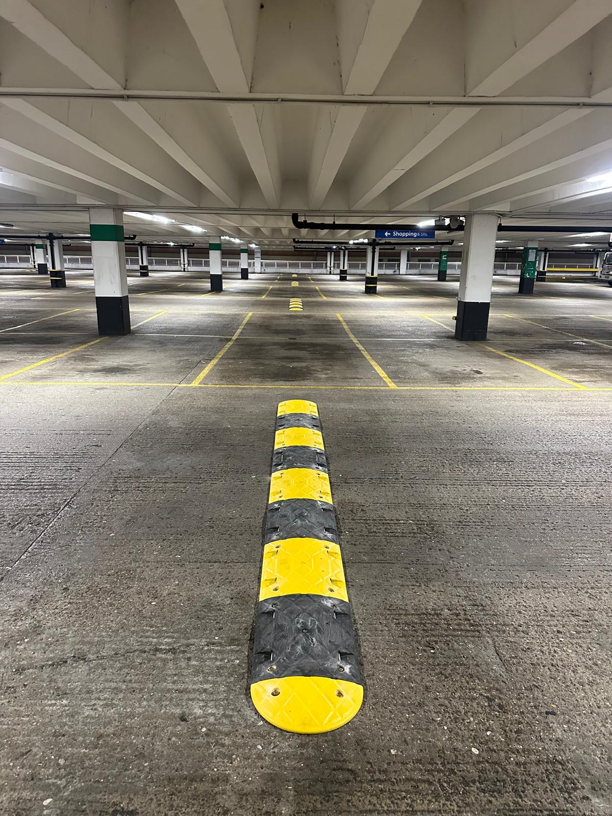 Rubber speed bump fitted on a concrete car park floor near structural columns