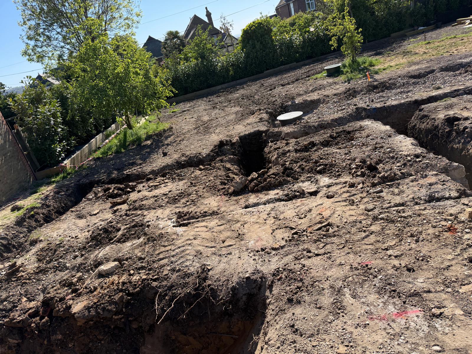 Newly excavated foundation trenches across a cleared commercial building plot
