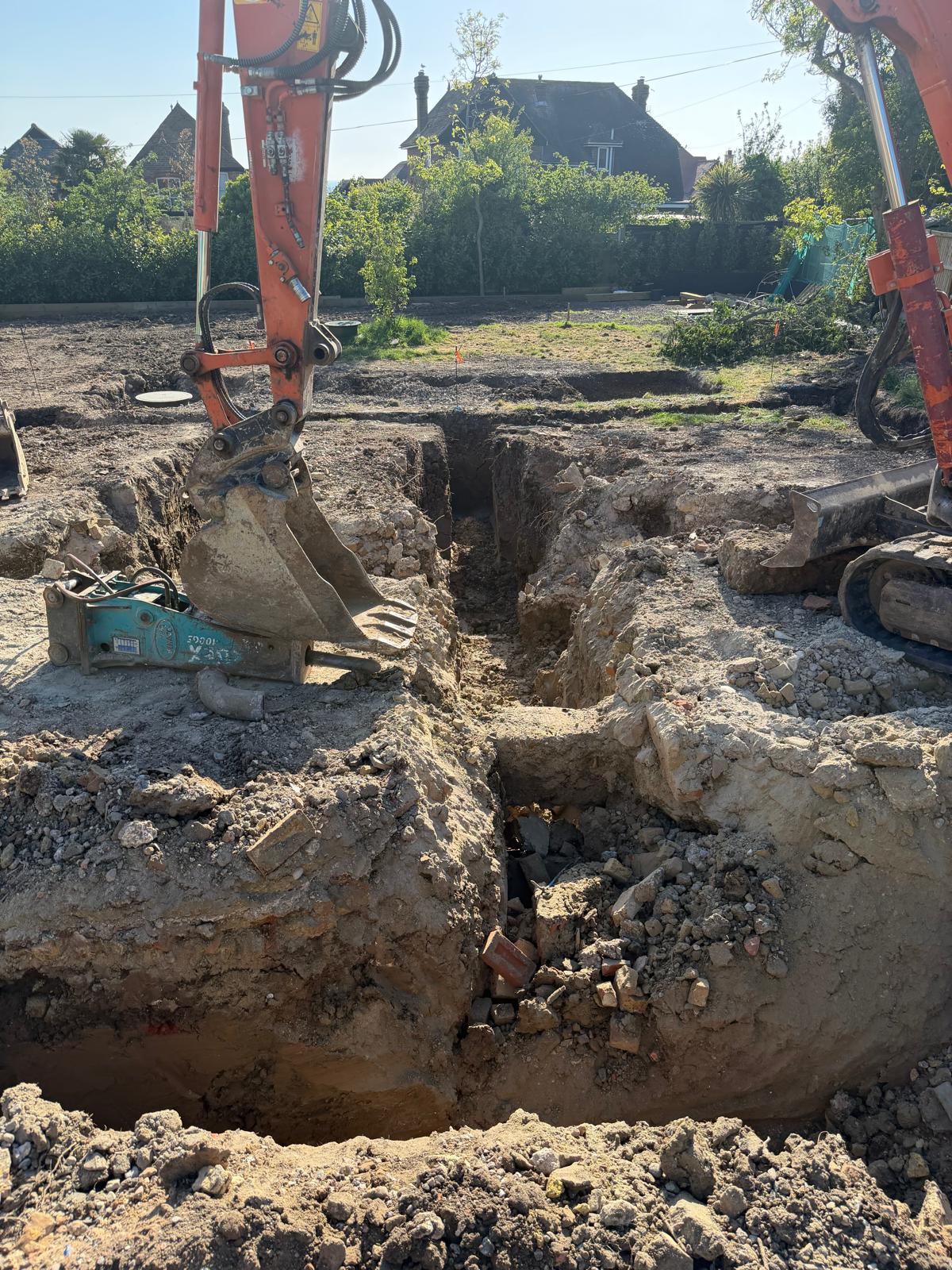 Deep foundation excavation running beside a brick boundary wall
