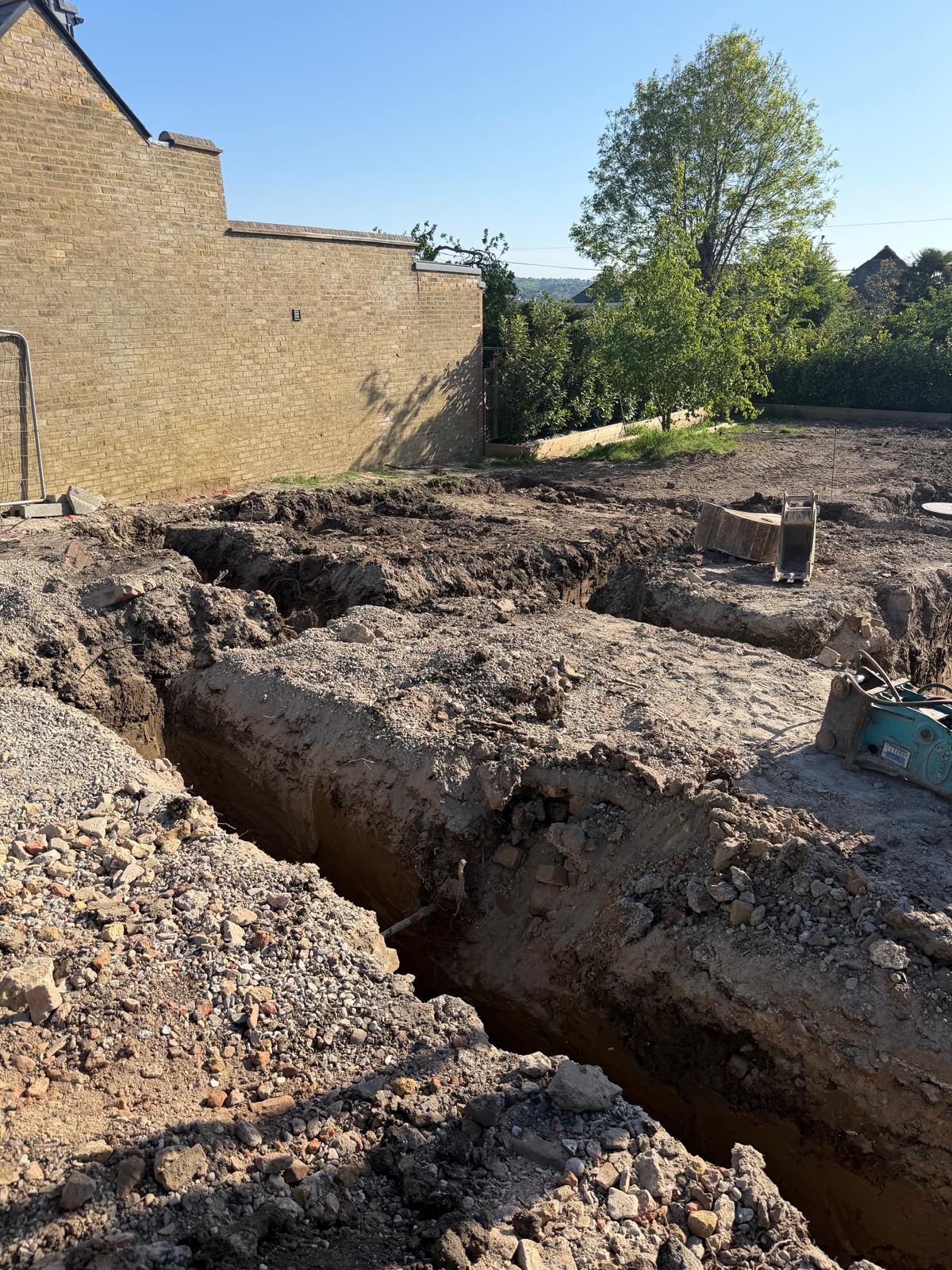 Long strip footing trench excavated along a yellow brick commercial building