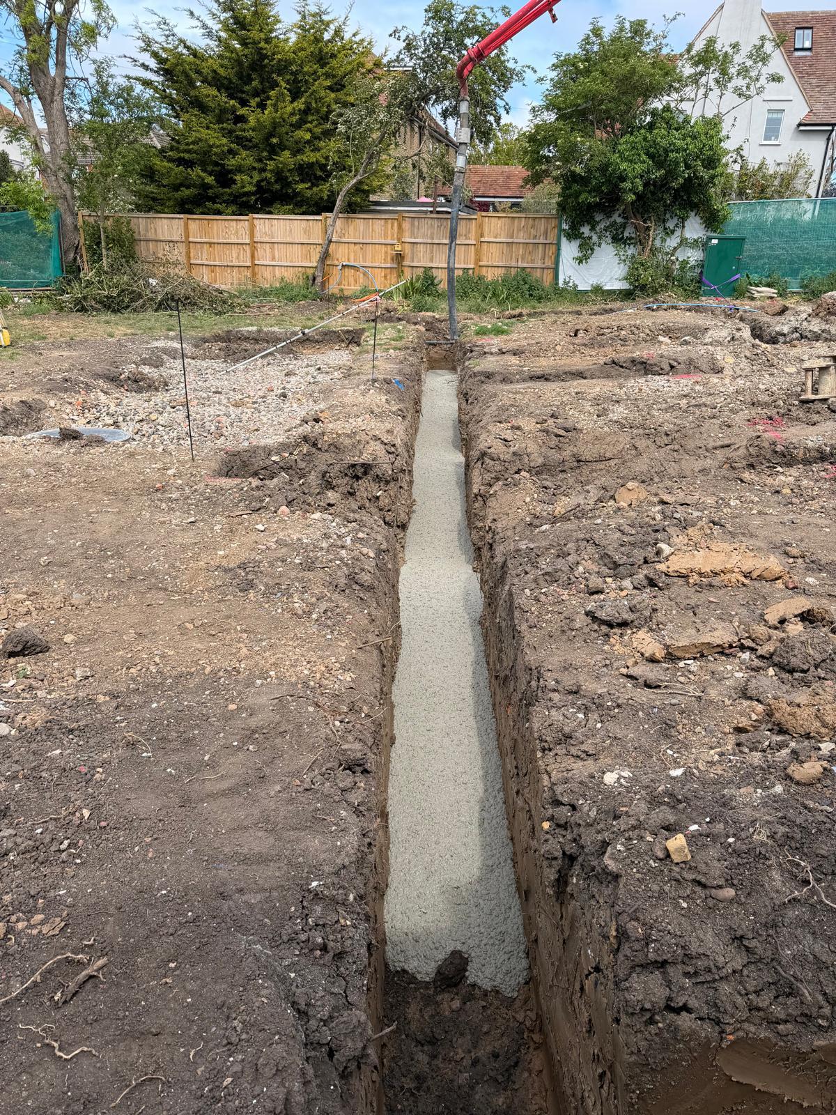 Groundworks excavation with excavator buckets staged beside foundation trenches