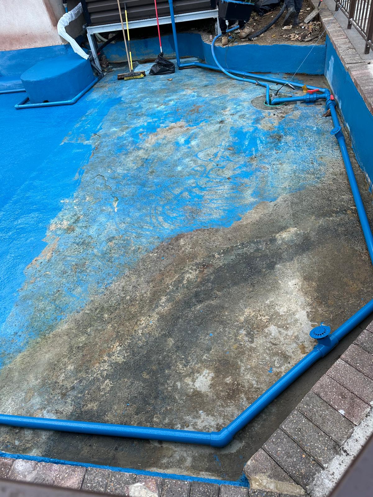 Pond floor being prepared with blue pipework, outlets and remaining old coating
