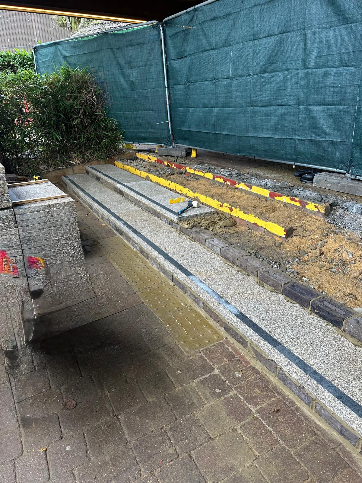 Broken-out stair treads and formation prepared beside tactile blister paving