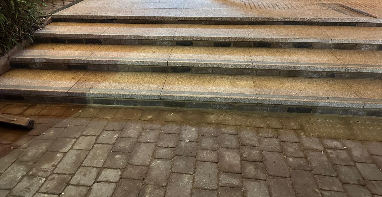 Stair repair in progress with excavated treads, brick edges and site hoarding