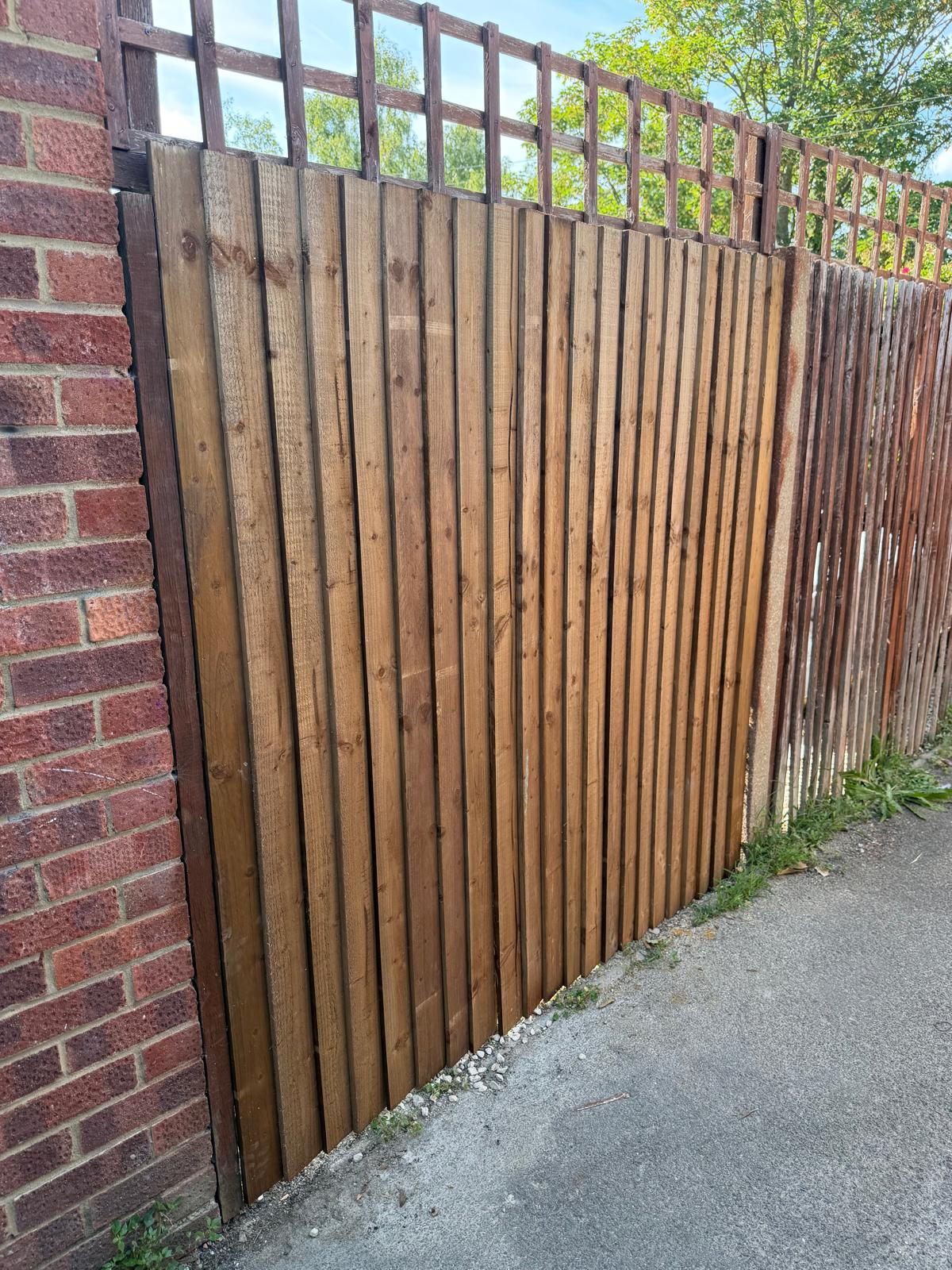 Timber fence panel installation with trellis topping on a garden boundary