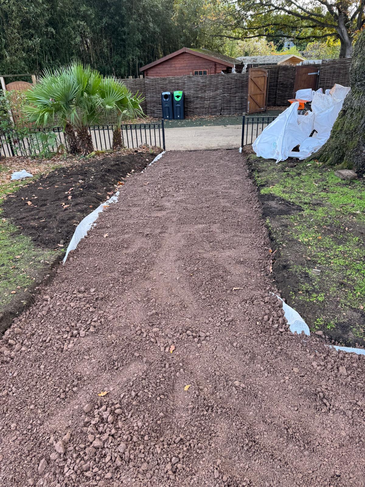 Compacted MOT type 1 stone sub-base laid for a public access footpath towards a wooden gate