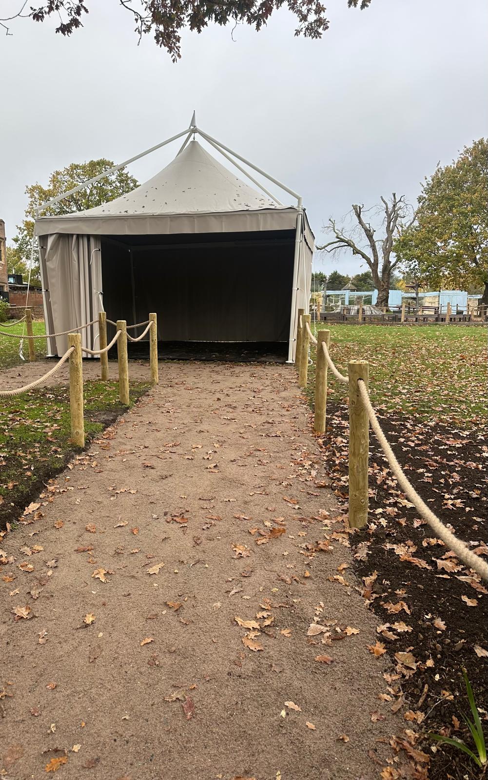 Sand public footpath with rope-and-post barriers leading to a marquee entrance