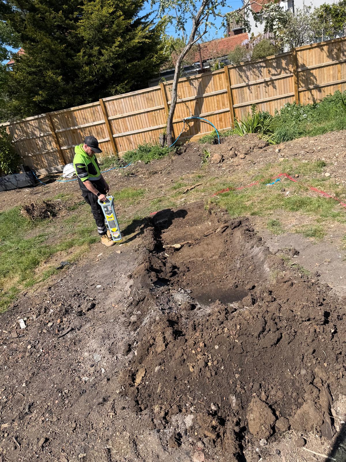 Engineer using a CAT scanner to locate buried services before rainwater tank excavation